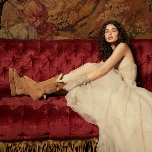 woman-sitting-on-the-couch-while-wearing-dress-and-tall-ugg-boots