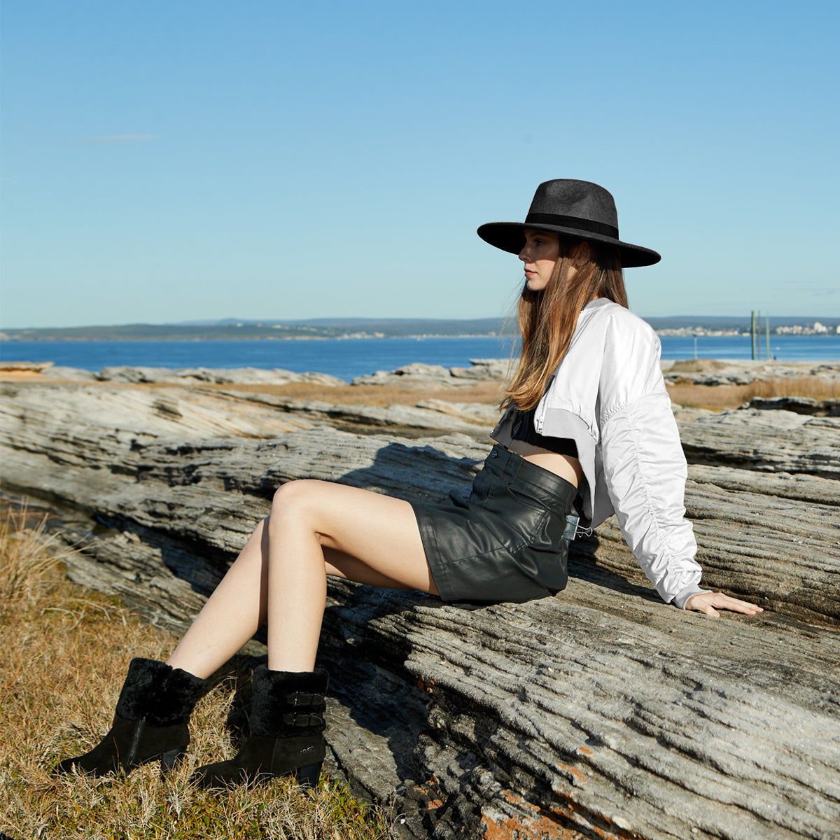 Australian woman near the shore wearing black-and-white outfit with black UGG boots