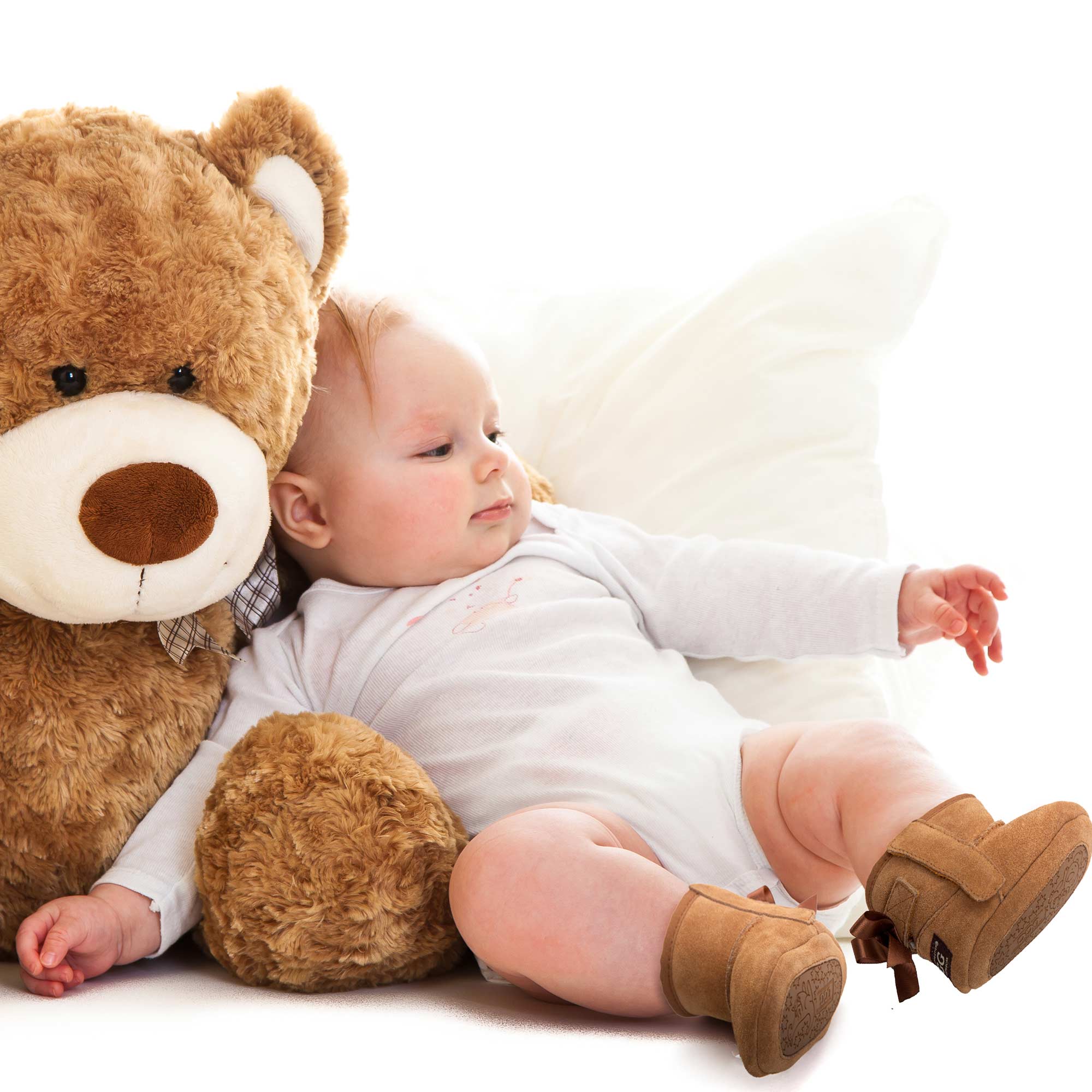 baby laying on a teddy bear while wearing UGG boot for infants